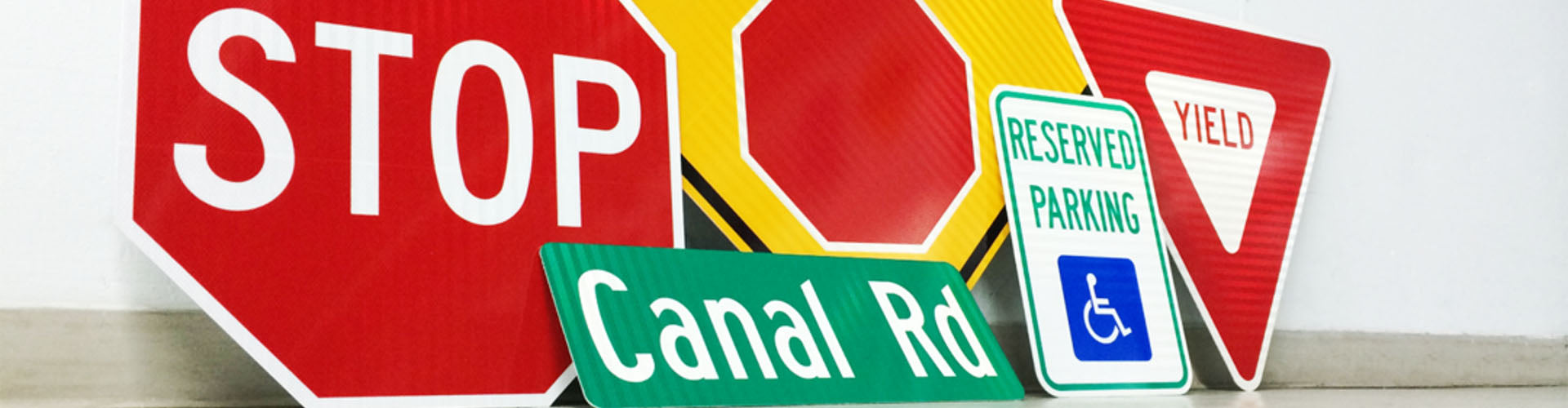 Array of street signs leaning against a wall